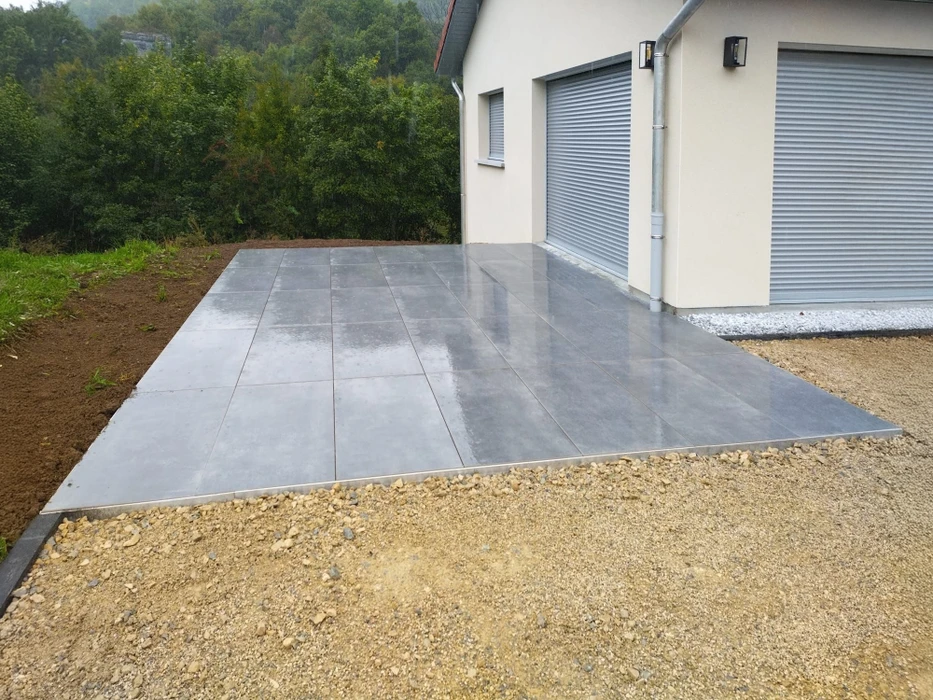Terrasse extérieure aménagée avec salon de jardin en rotin naturel comprenant deux fauteuils et table basse ronde