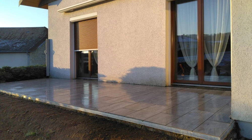 Terrasse extérieure aménagée avec salon de jardin en résine tressée, table et chaises pour repas en plein air