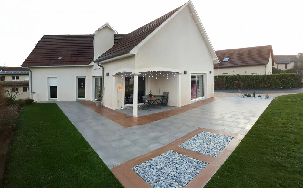 Terrasse extérieure aménagée avec salon de jardin en bois teck comprenant canapé deux places, deux fauteuils assortis avec coussins beiges, table basse carrée massive