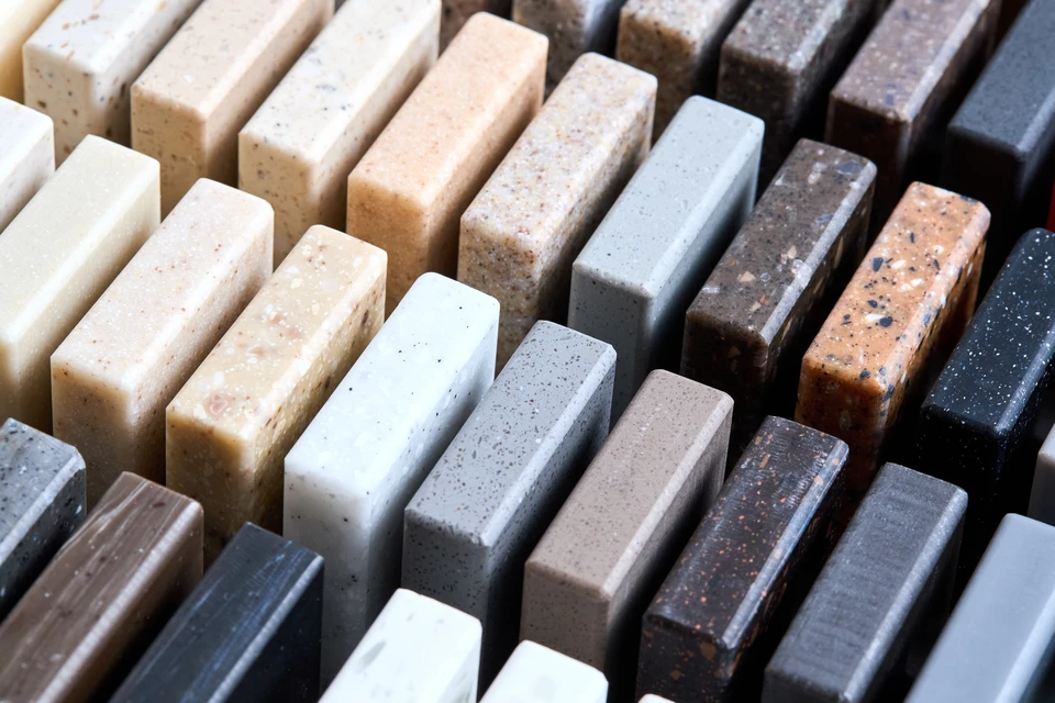 Chantier extérieur au bord de l'eau avec empilage de dalles en pierre naturelle beige organisées en plusieurs piles régulières sur surface bétonnée