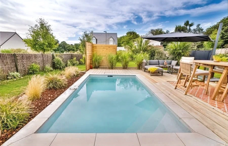 Piscine privée illuminée la nuit dans un jardin tropical luxueux, entourée de végétation dense et palmiers