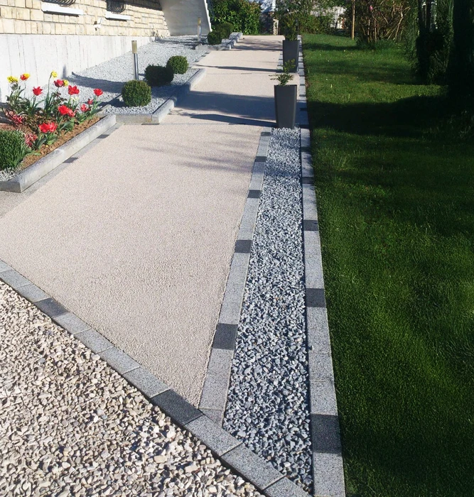 Jardin paysagé avec allée courbe en pavés de béton traversant une pelouse verte impeccable
