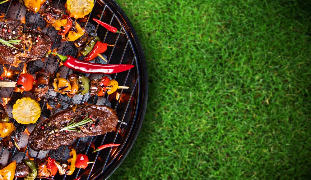 Scène extérieure de barbecue sur pelouse verte avec grillades en cours