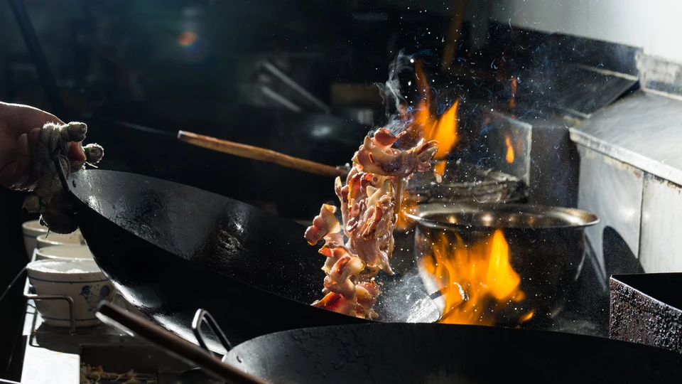 Cuisinier professionnel flambant des aliments dans une cuisine commerciale