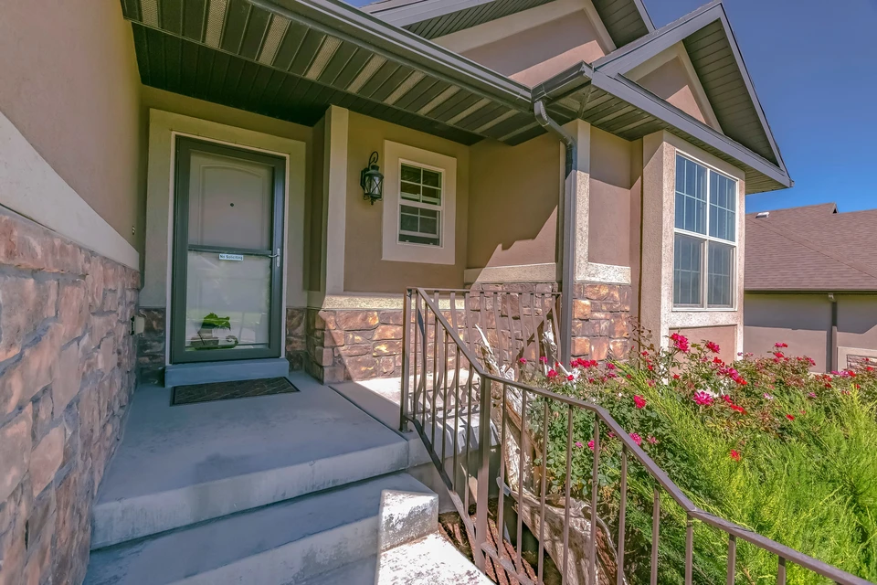 Entrée résidentielle avec escalier béton, rampe métallique décorative et porte d'entrée moderne
