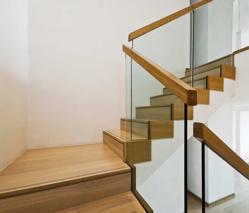 Escalier moderne en bois clair avec garde-corps en verre trempé et main courante en chêne