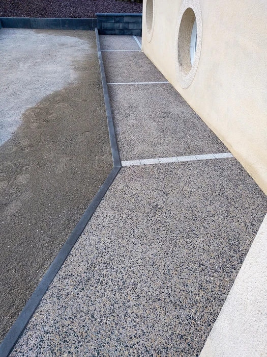 Allée de gravier menant à une maison en briques rouges avec jardinage paysager