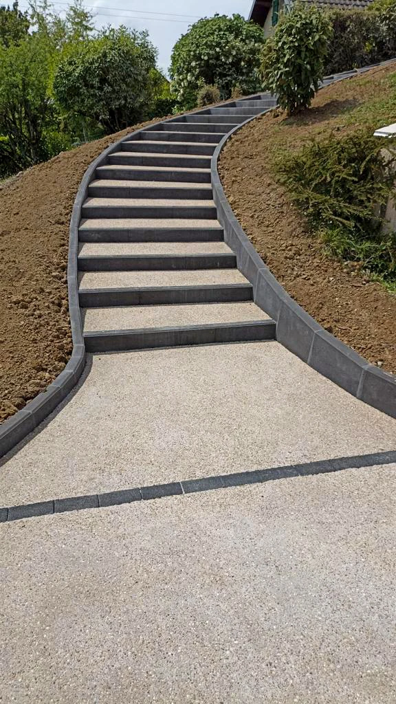 Entrée extérieure d'habitation moderne avec escalier en bois exotique, rampe métallique design et jardinières alignées contenant des plantes tropicales colorées